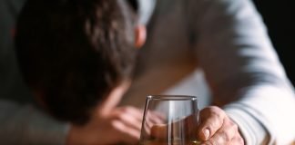 Bicchiere vino con uomo ubriaco sullo sfondo